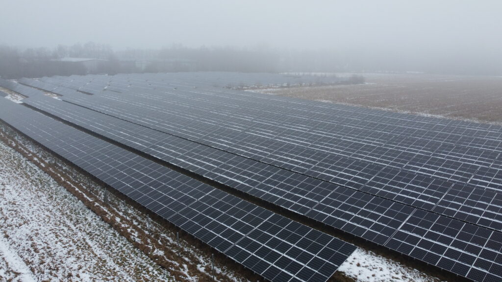 Luftaufnahme eines Solarparks in Schwindegg mit langen Reihen von Photovoltaik-Modulen